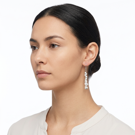 Modelka z wąskim wiszącym kolczykiem z białych odłamków na białym tle